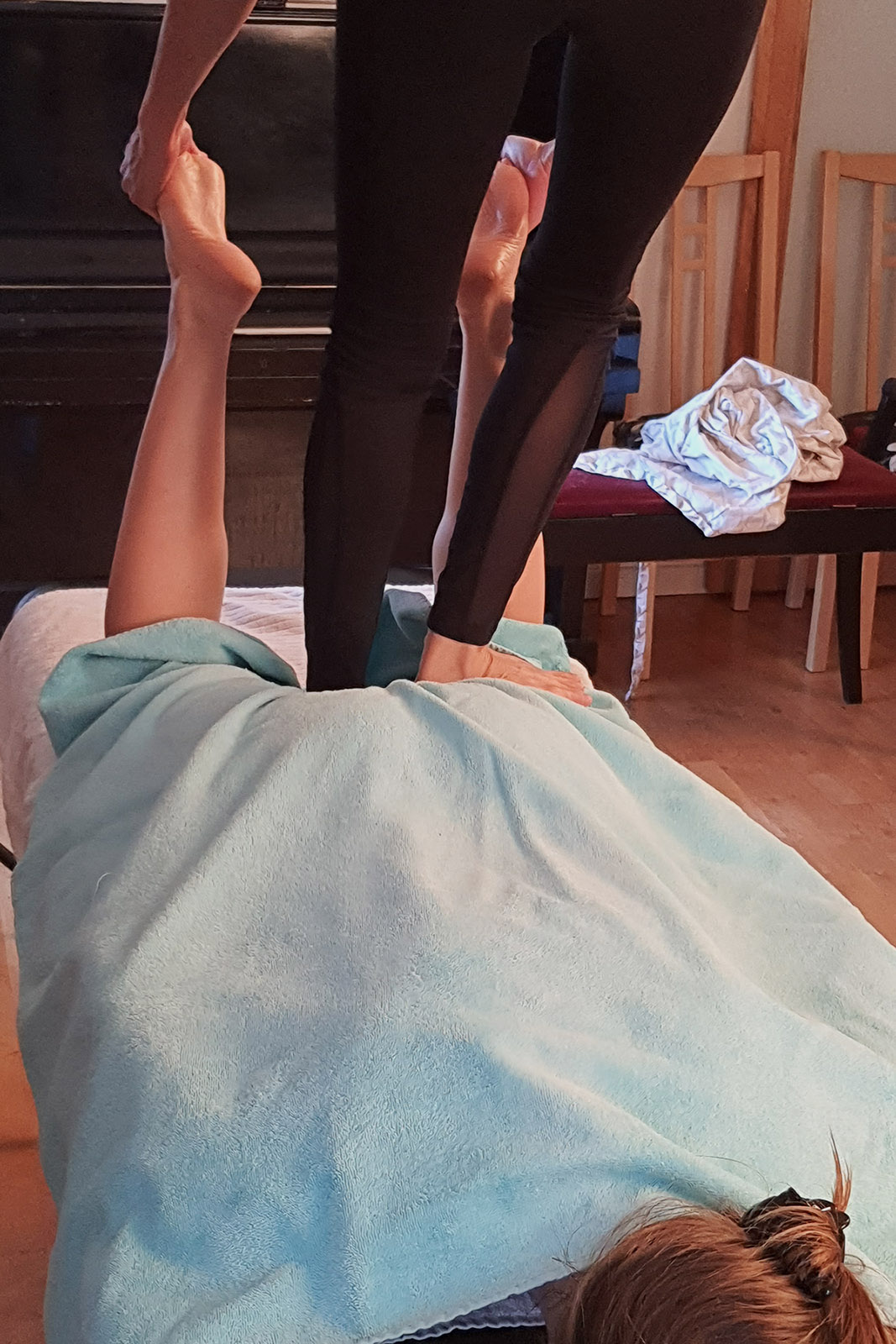 Nok använder hela sin kropp när hon gör sin thaimassage. Här står hon på baksidan av massageobjektets ena lår och stretchar fötterna och framsidan av låren.